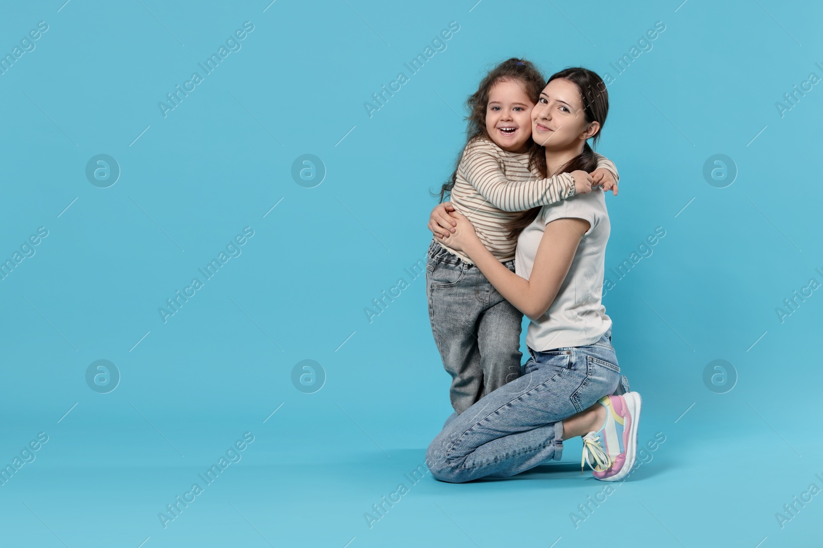 Photo of Portrait of cute sisters on light blue background, space for text