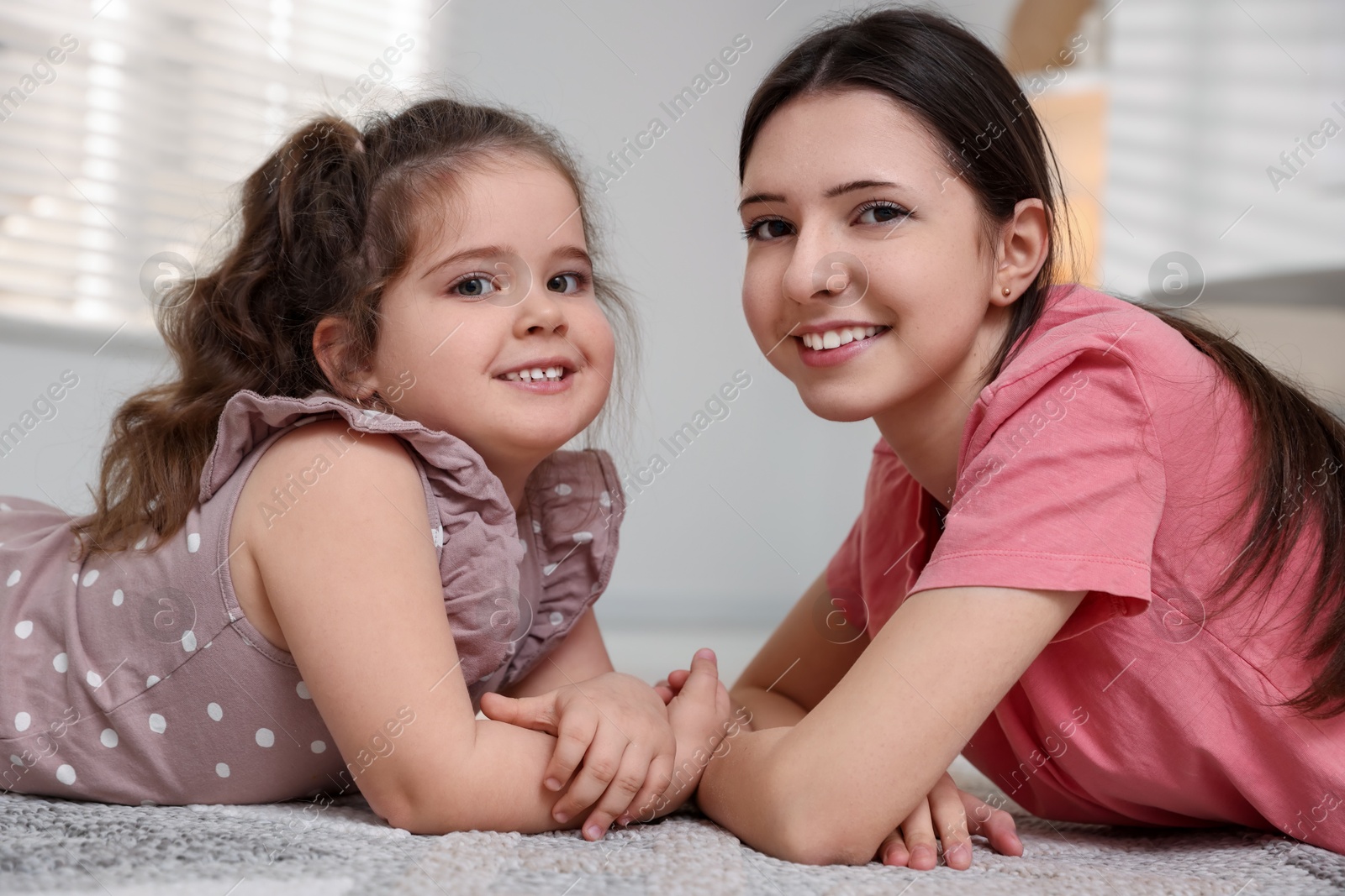 Photo of Portrait of cute little girl and her sister indoors