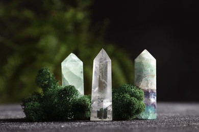 Photo of Natural gemstones and moss on grey textured table, closeup