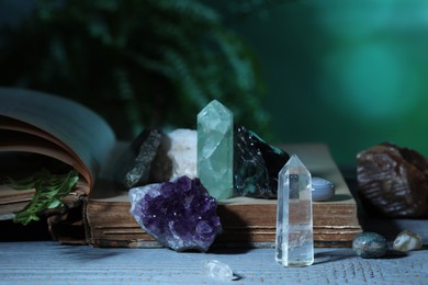 Photo of Beautiful natural gemstones and book on grey table against green background