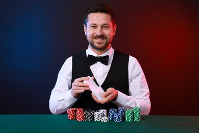 Photo of Professional croupier shuffling cards at gambling table