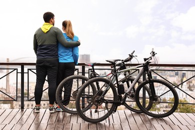 Photo of Beautiful happy couple with bicycles spending time together outdoors, back view