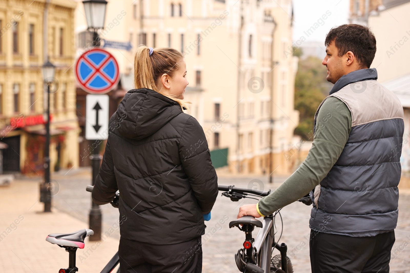 Photo of Couple with bicycles spending time together outdoors, back view