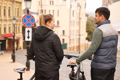 Photo of Couple with bicycles spending time together outdoors, back view