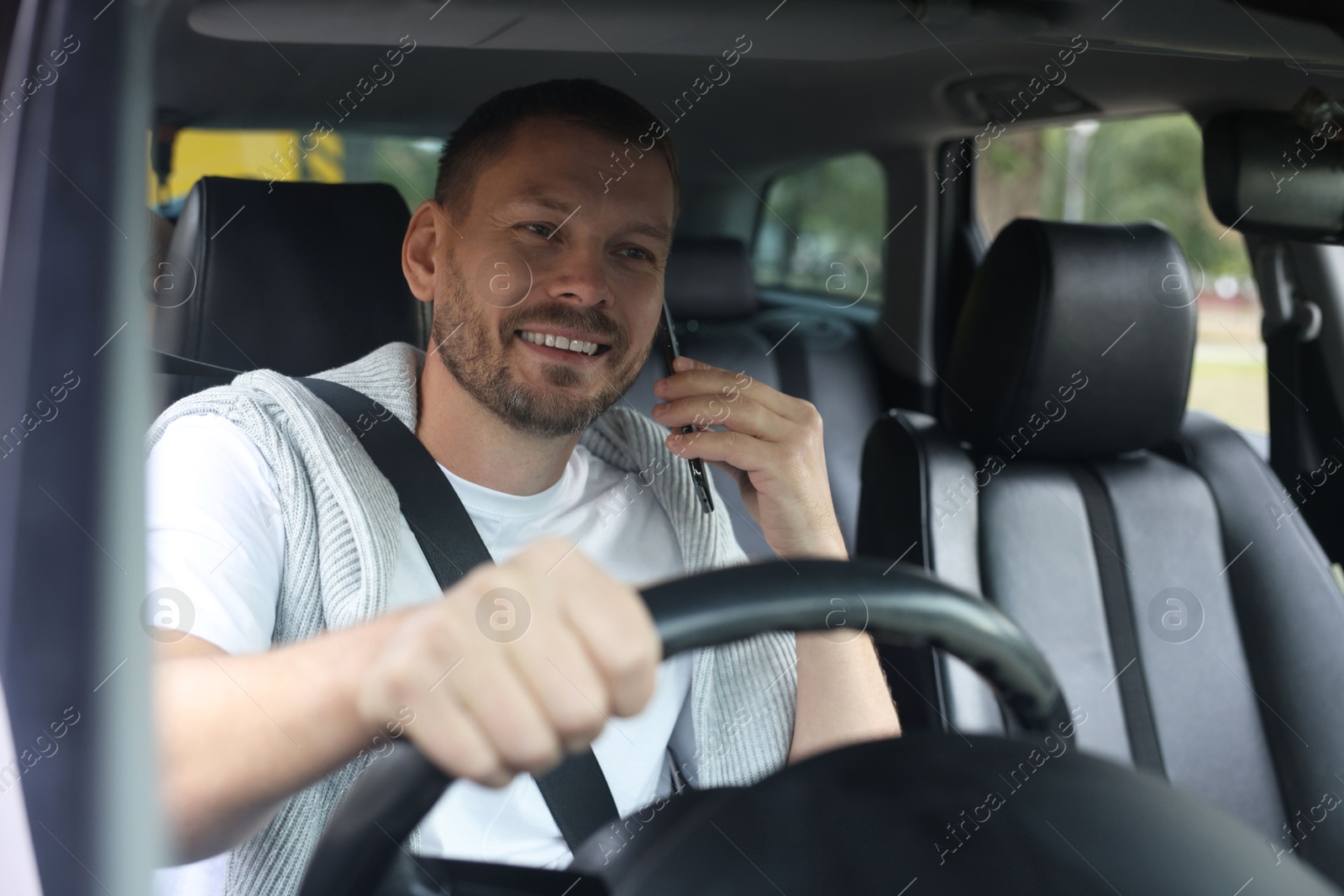 Photo of Man talking on phone while driving modern car, view through windshield