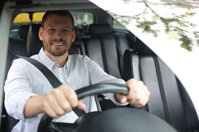 Photo of Happy man behind steering wheel of modern car, view through windshield