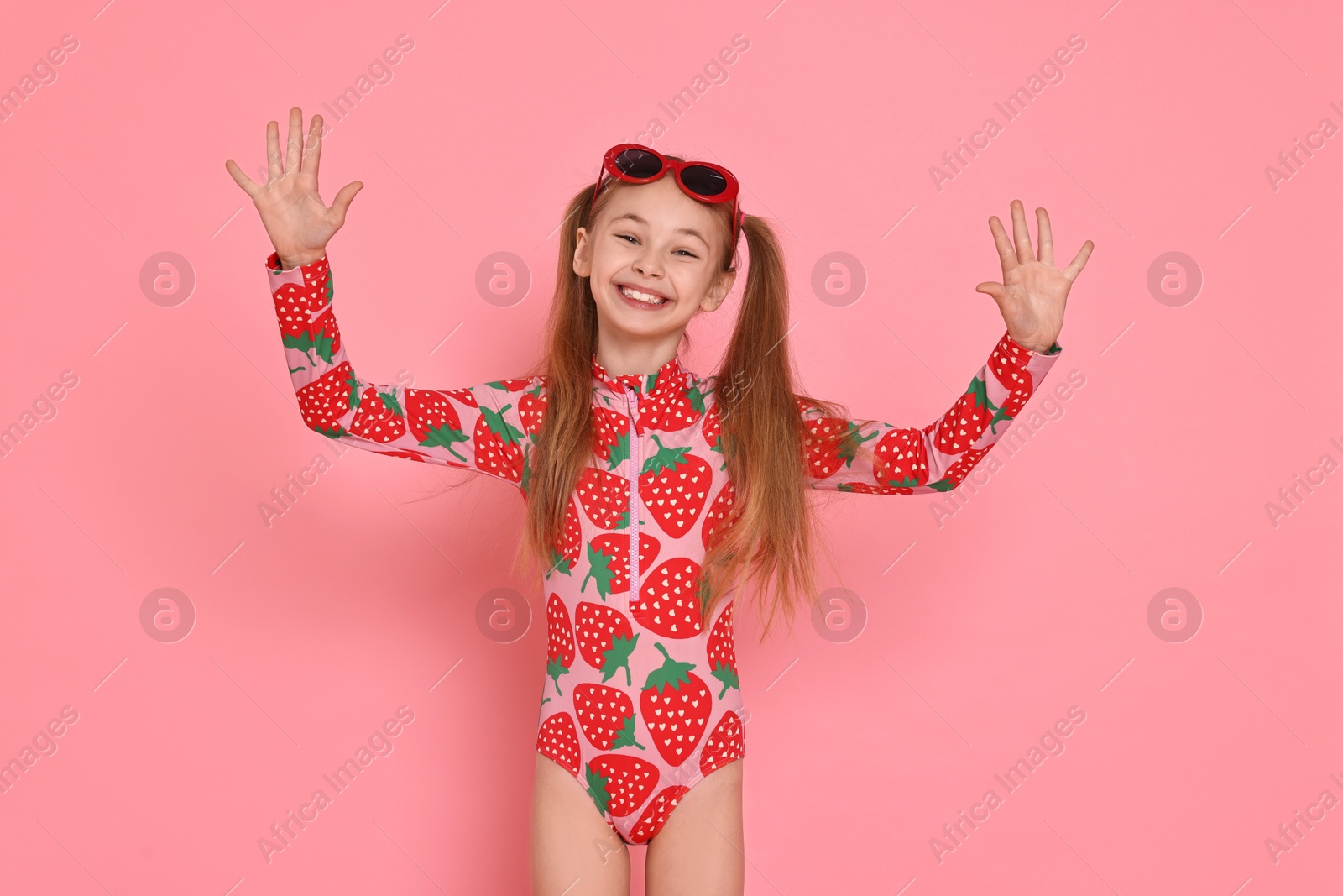 Photo of Happy girl in beachwear and sunglasses on pink background