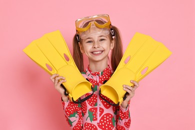 Photo of Little girl in beachwear with diving mask and flippers on pink background