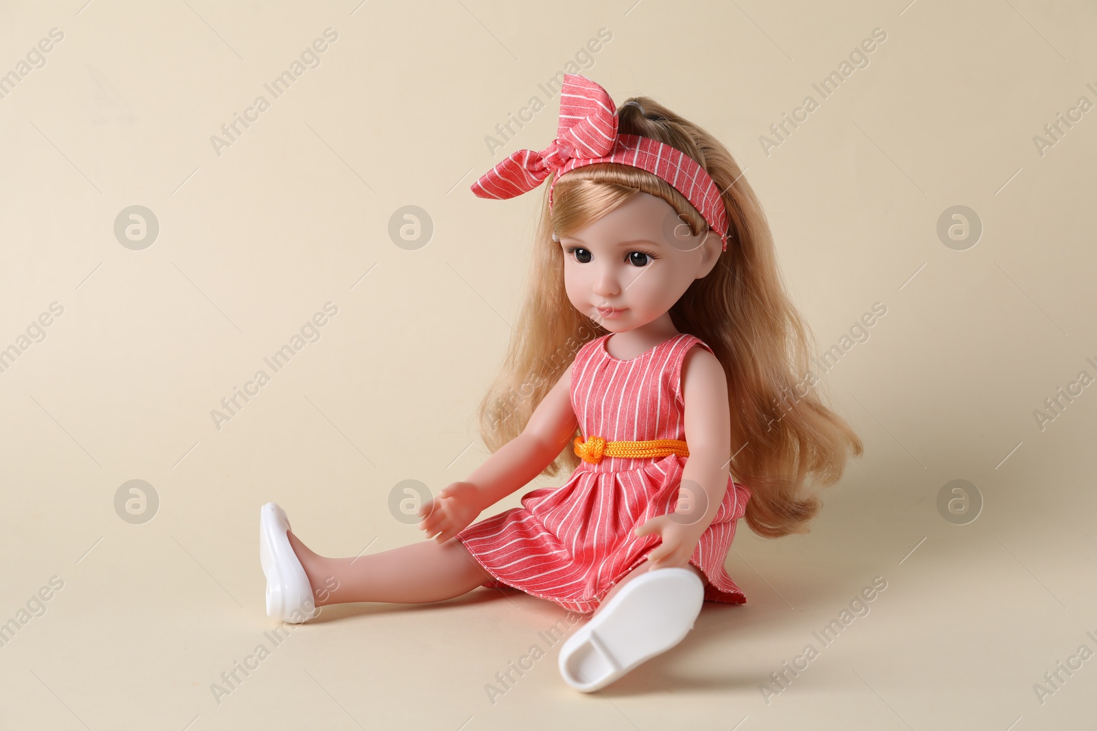 Photo of Beautiful doll in dress and headband on beige background