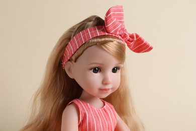 Beautiful doll with headband on beige background, closeup