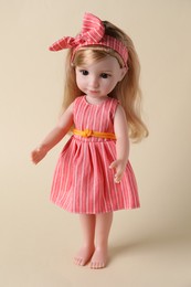 Beautiful doll in dress and headband on beige background