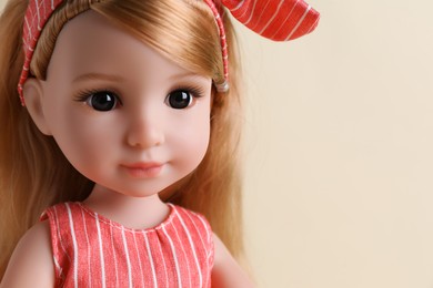 Beautiful doll with headband on beige background, closeup. Space for text