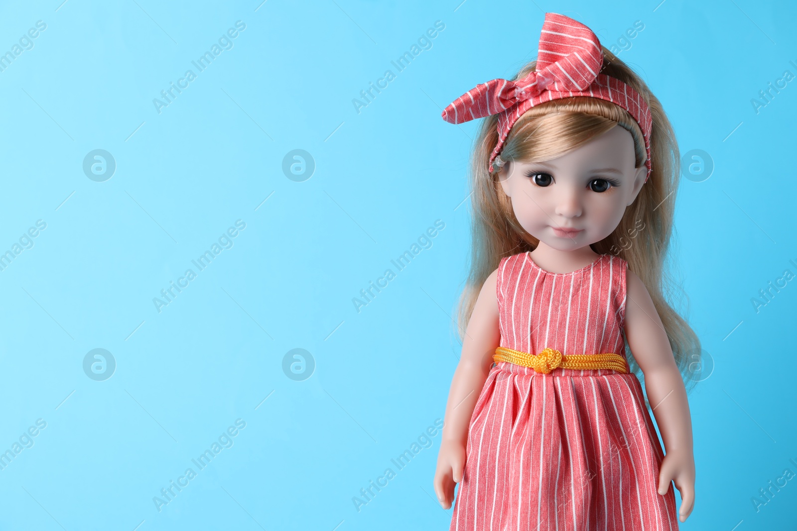 Photo of Beautiful doll in dress and headband on light blue background. Space for text