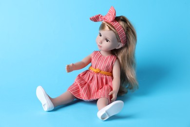 Photo of Beautiful doll in dress and headband on light blue background