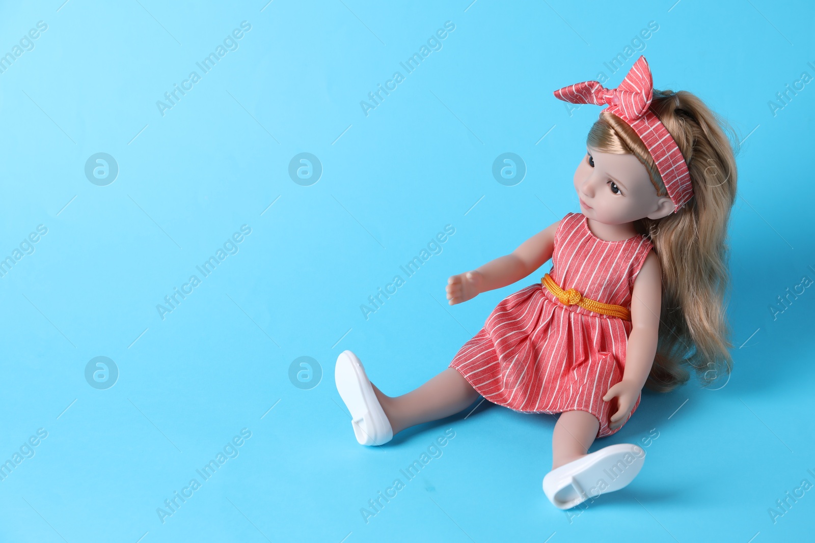 Photo of Beautiful doll in dress and headband on light blue background. Space for text