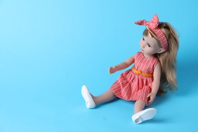 Beautiful doll in dress and headband on light blue background. Space for text