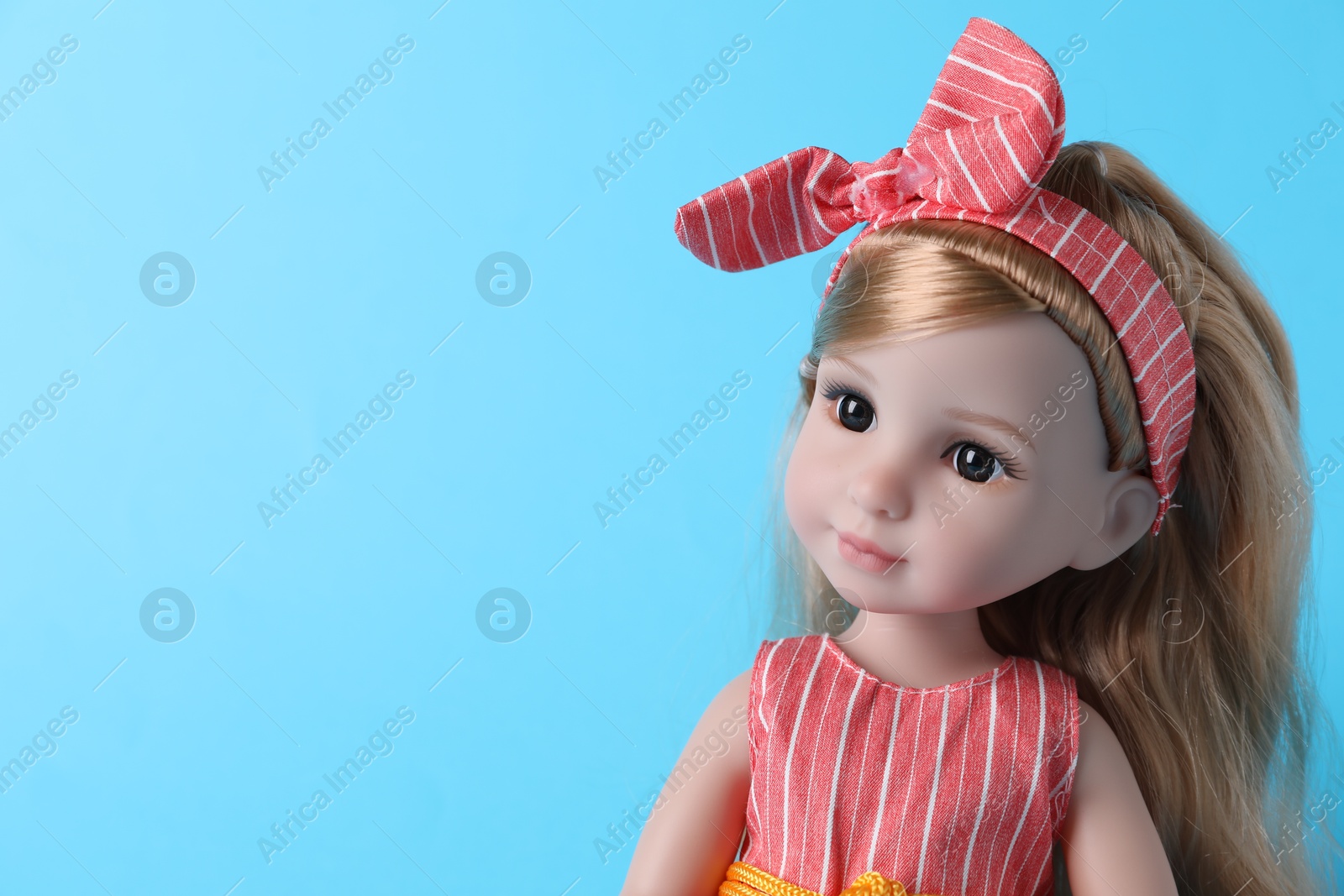 Photo of Beautiful doll with headband on light blue background, closeup. Space for text