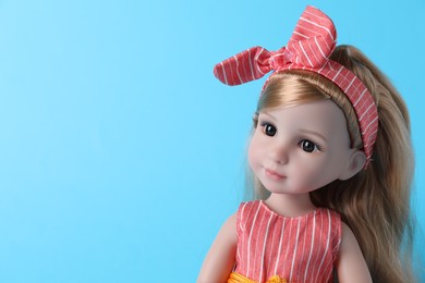 Photo of Beautiful doll with headband on light blue background, closeup. Space for text