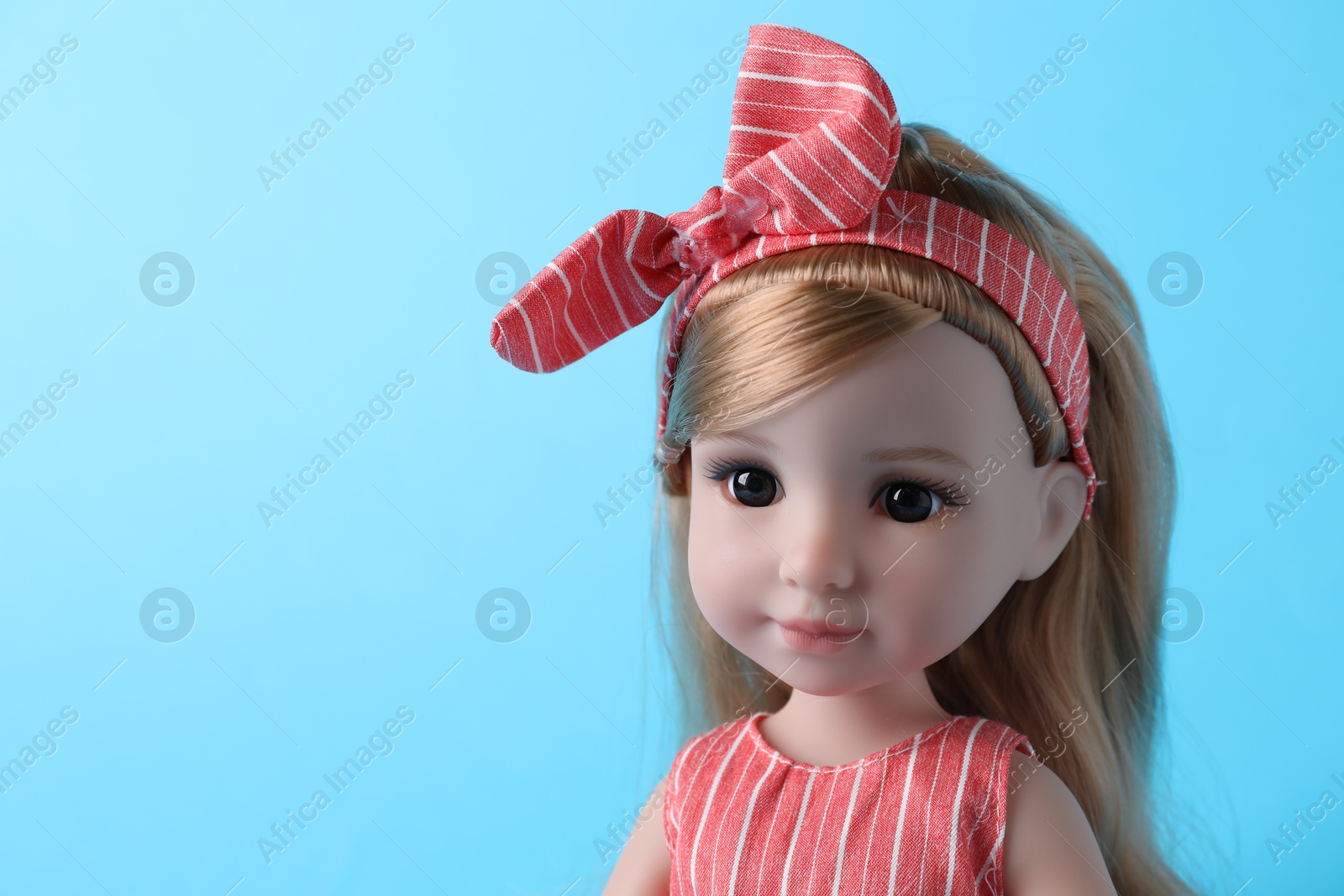 Photo of Beautiful doll with headband on light blue background, closeup. Space for text