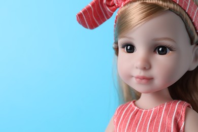 Beautiful doll with headband on light blue background, closeup. Space for text