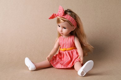 Photo of Beautiful doll in dress and headband on light brown background