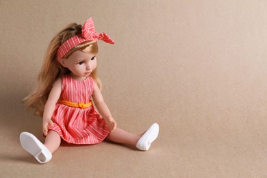 Beautiful doll in dress and headband on light brown background. Space for text