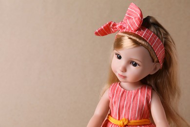 Photo of Beautiful doll with headband on light brown background, closeup. Space for text