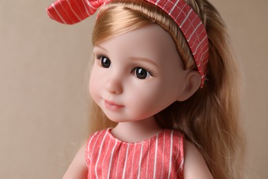 Photo of Beautiful doll with headband on light brown background, closeup