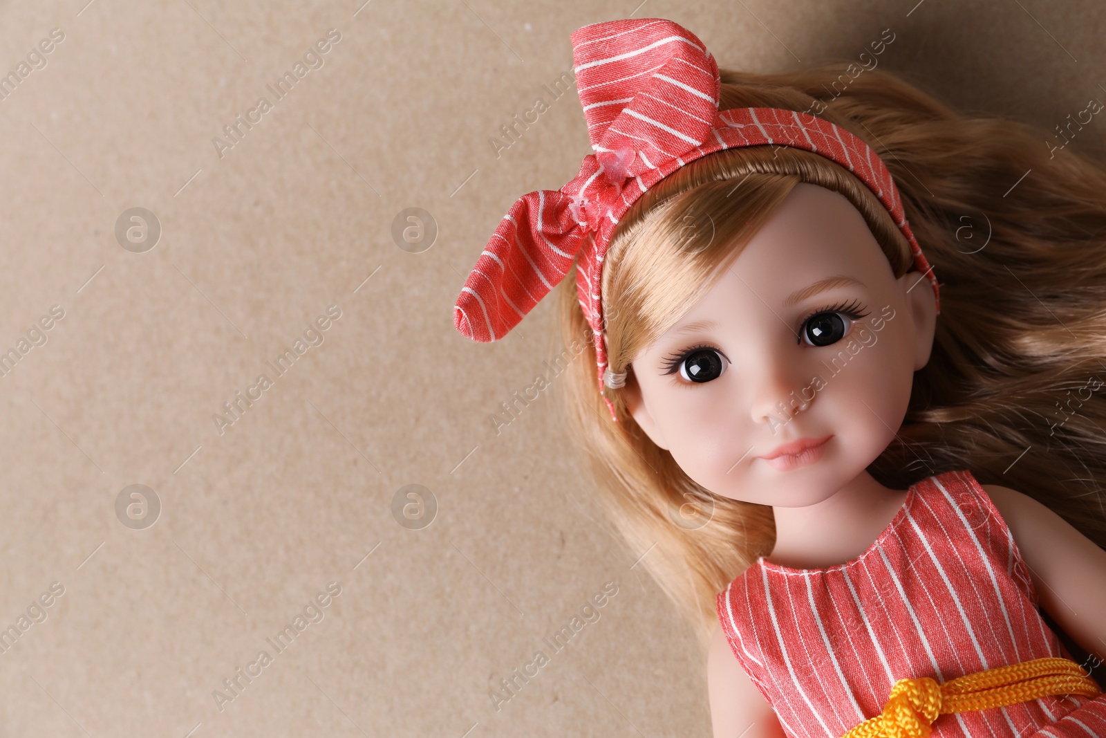 Photo of Beautiful doll with headband on light brown background, top view. Space for text