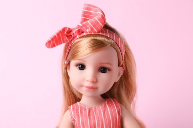 Photo of Beautiful doll with headband on pink background, closeup