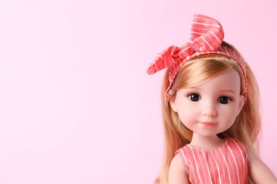 Beautiful doll with headband on pink background, closeup. Space for text