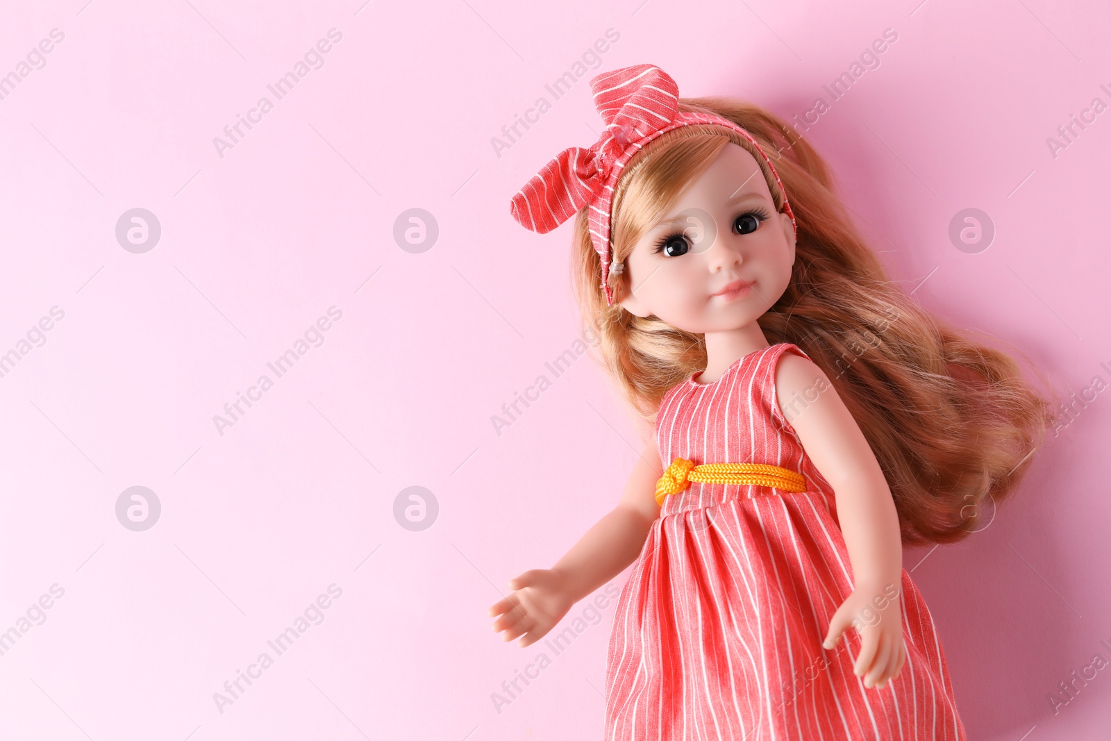 Photo of Beautiful doll in dress and headband on pink background, top view. Space for text