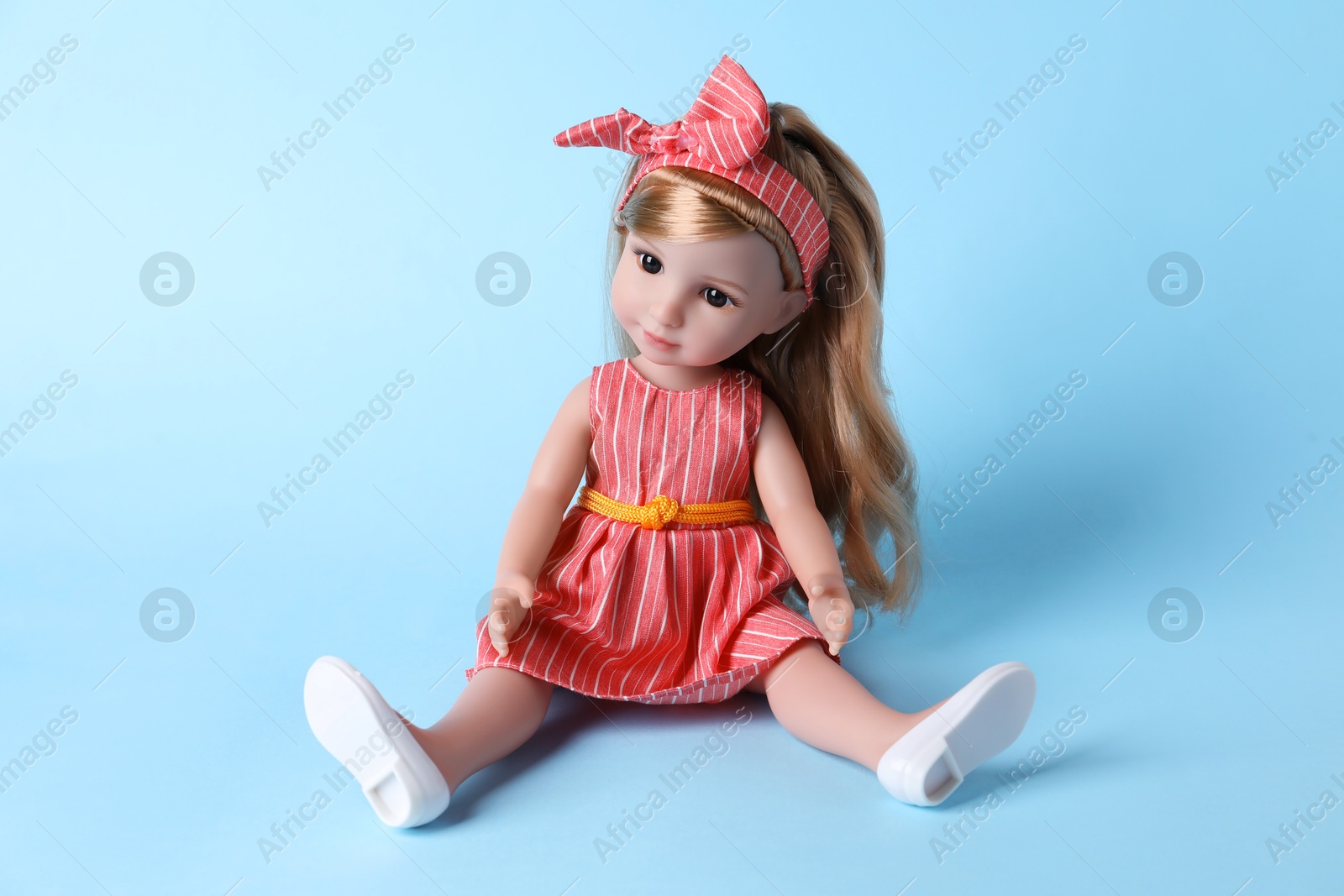 Photo of Beautiful doll in dress and headband on light blue background