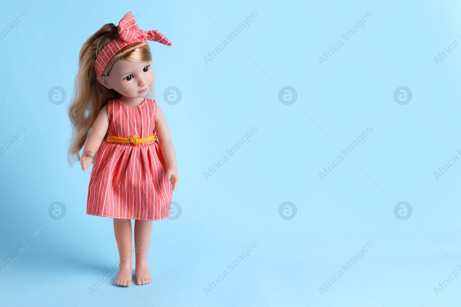 Photo of Beautiful doll in dress and headband on light blue background. Space for text