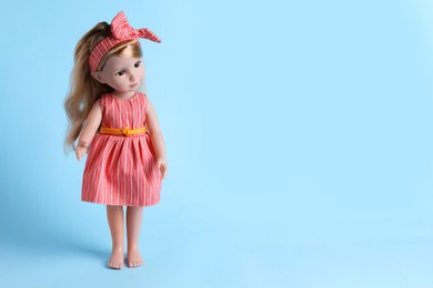 Beautiful doll in dress and headband on light blue background. Space for text