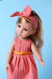 Photo of Beautiful doll in dress and headband on light blue background