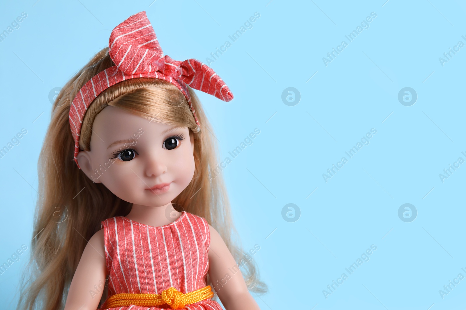 Photo of Beautiful doll with headband on light blue background, closeup. Space for text