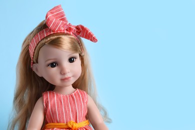 Beautiful doll with headband on light blue background, closeup. Space for text