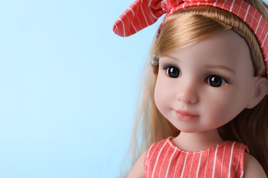 Photo of Beautiful doll with headband on light blue background, closeup. Space for text