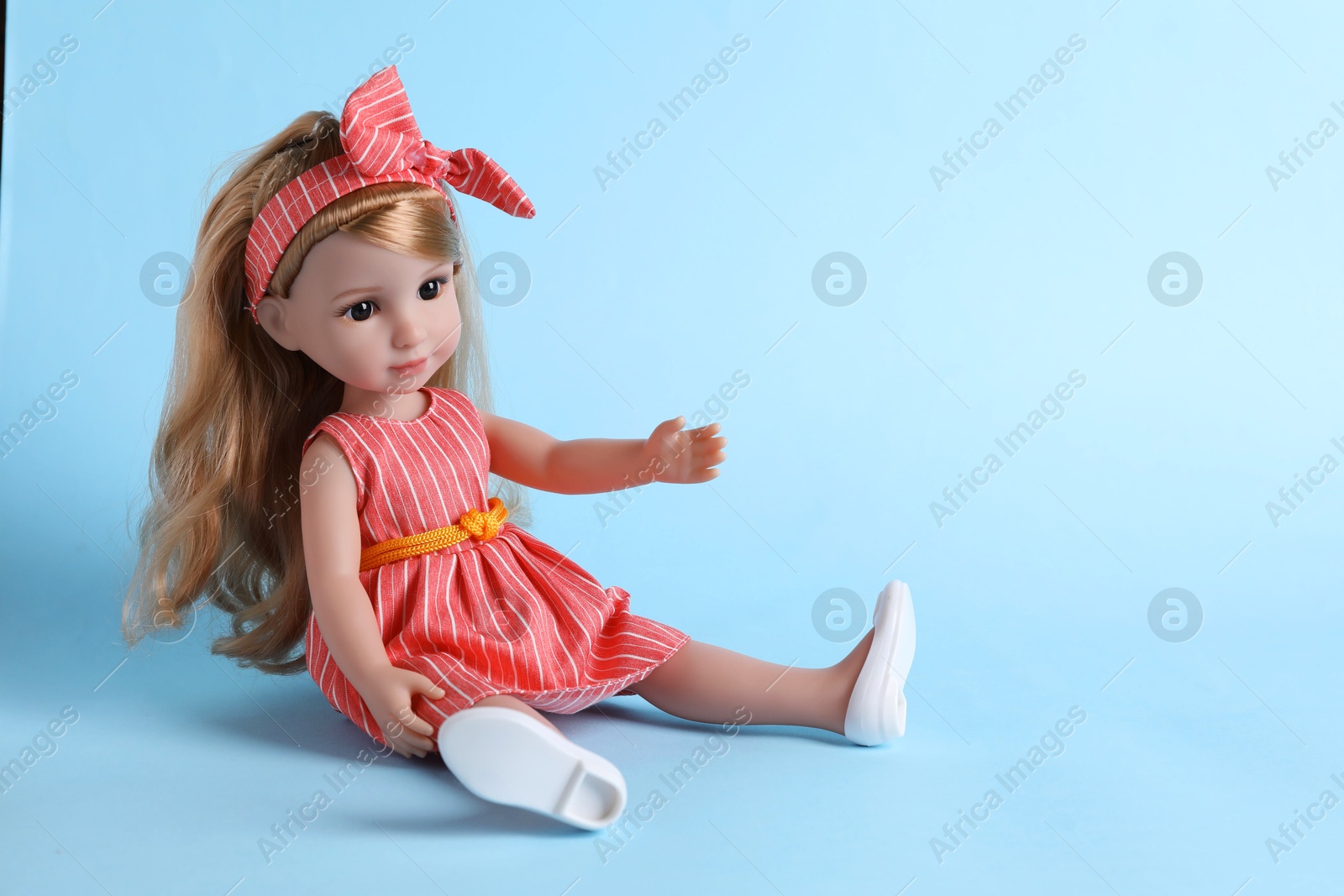 Photo of Beautiful doll in dress and headband on light blue background. Space for text