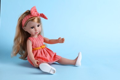 Photo of Beautiful doll in dress and headband on light blue background. Space for text