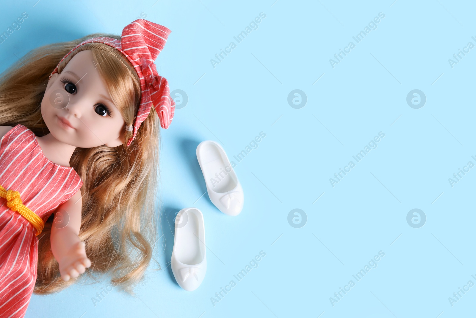 Photo of Beautiful doll in dress and shoes on light blue background, top view. Space for text