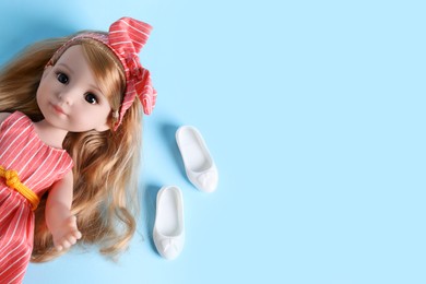 Photo of Beautiful doll in dress and shoes on light blue background, top view. Space for text