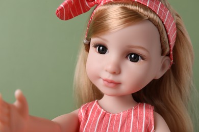 Photo of Beautiful doll with headband on light green background, closeup