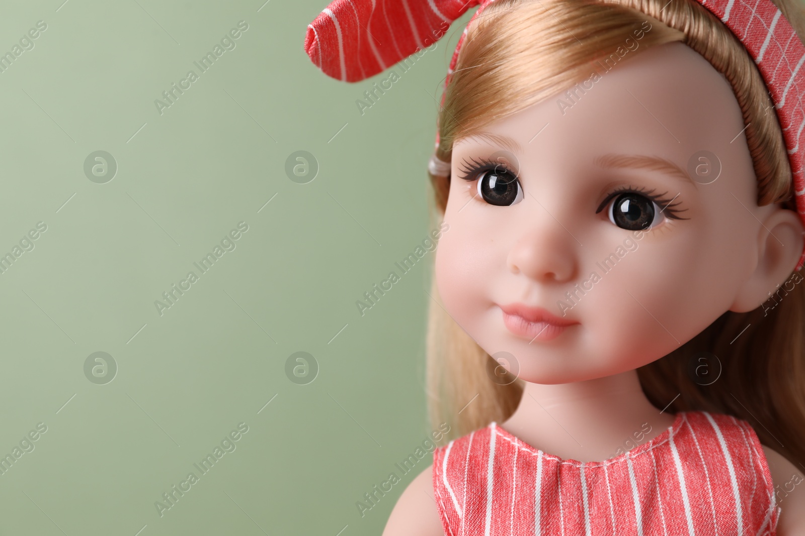 Photo of Beautiful doll with headband on light green background, closeup. Space for text