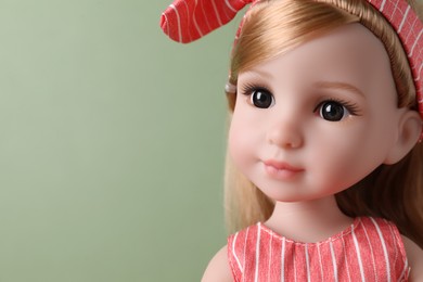 Beautiful doll with headband on light green background, closeup. Space for text