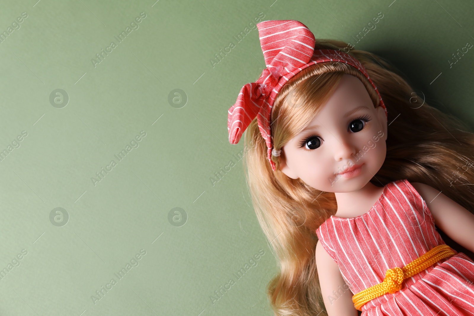 Photo of Beautiful doll in dress and headband on light green background, top view. Space for text