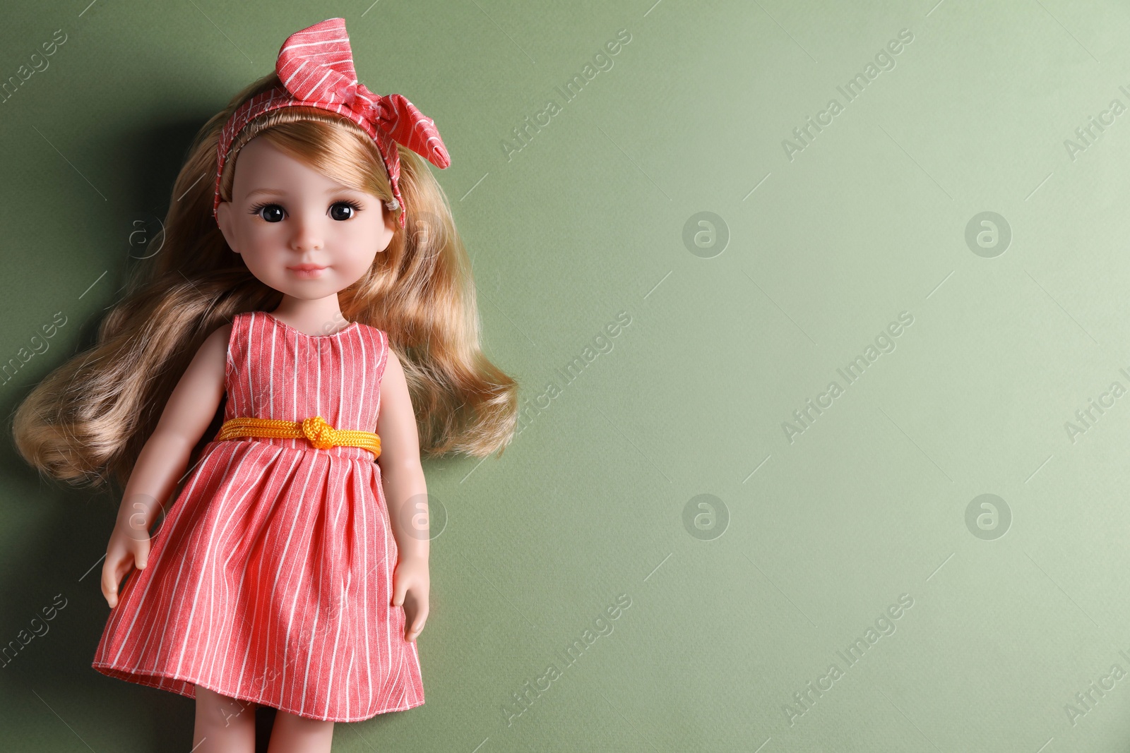 Photo of Beautiful doll in dress and headband on light green background, top view. Space for text