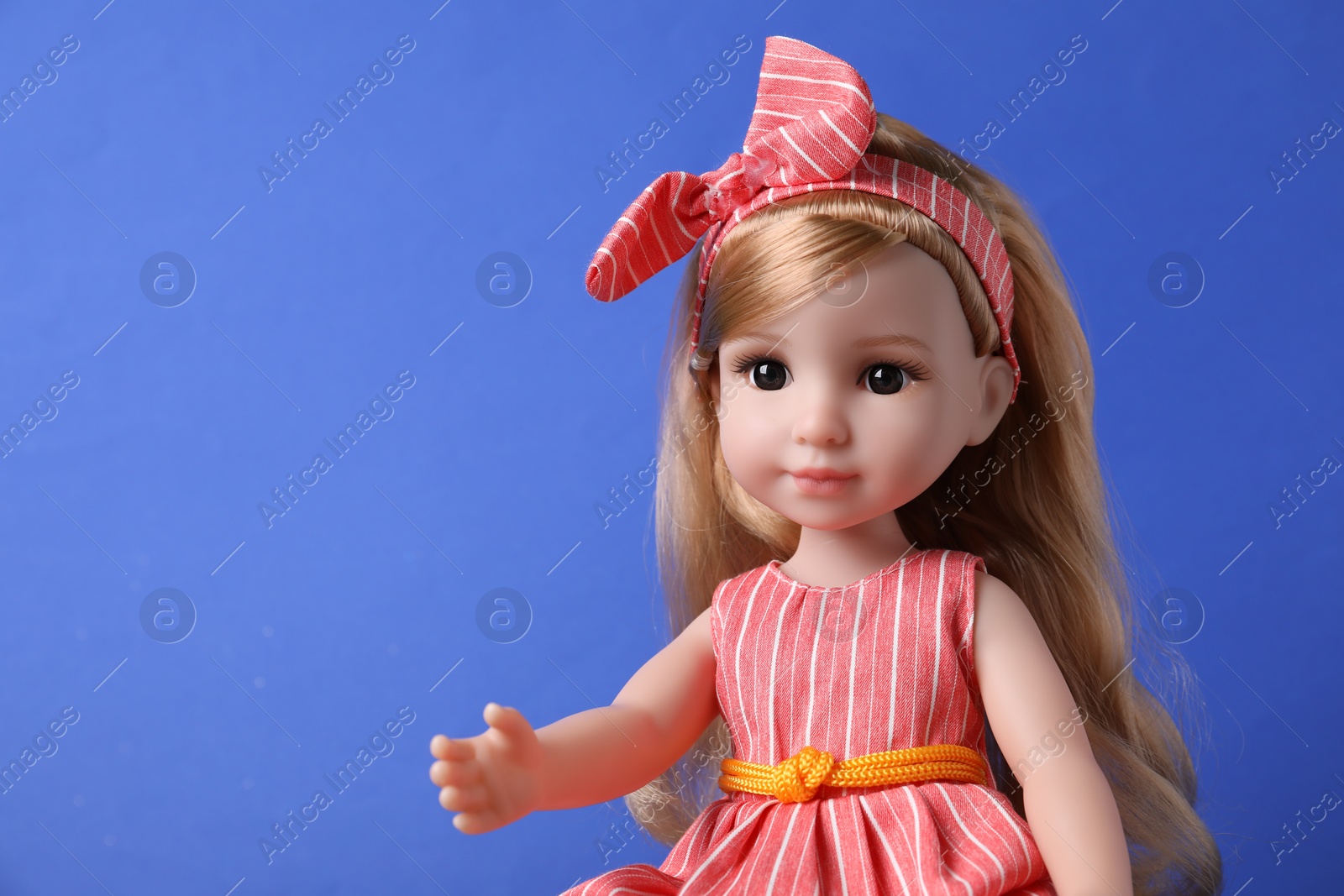 Photo of Beautiful doll in dress and headband on blue background, closeup. Space for text