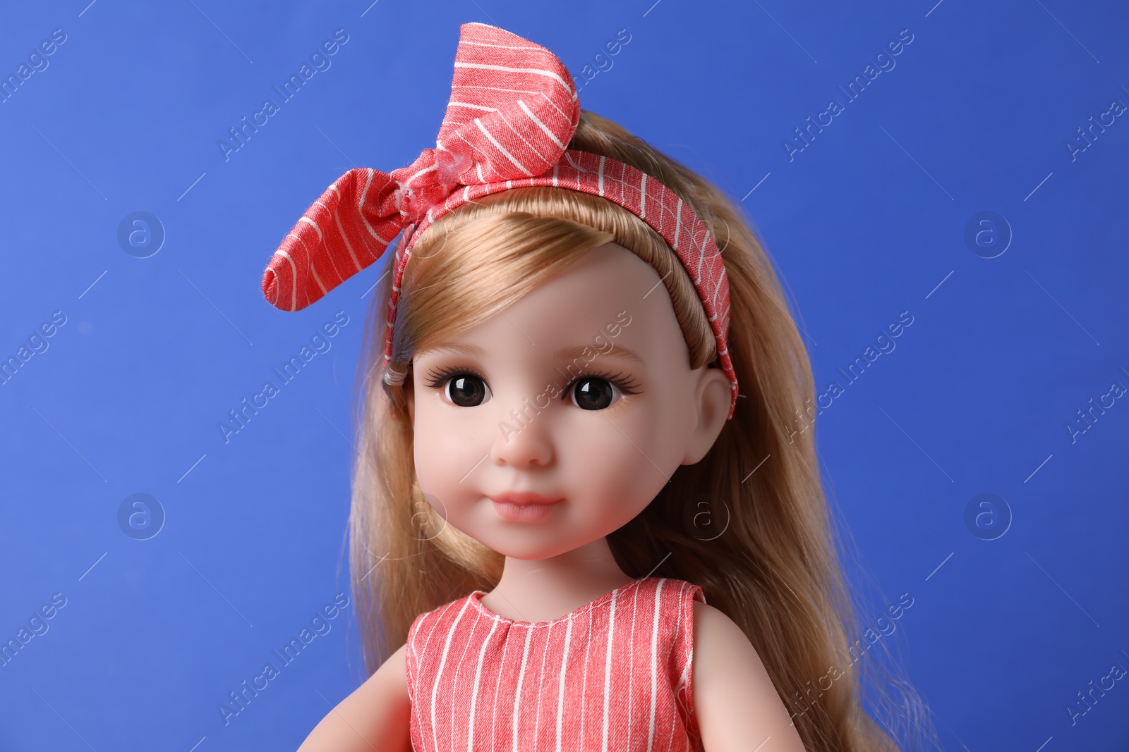 Photo of Beautiful doll in headband on blue background, closeup